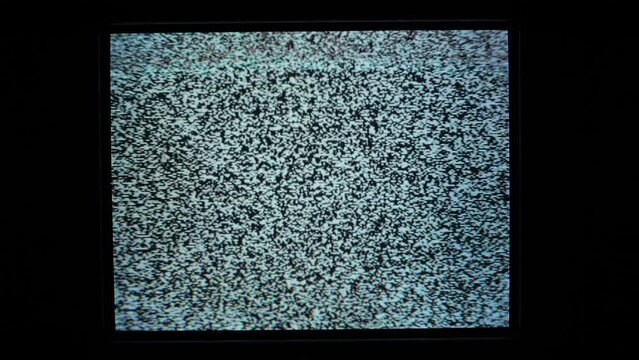 Static noise on an analog TV screen, signal lost. Zoom out.