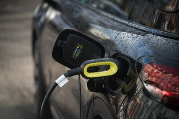 Closeup of black electric car charging at the station in the street - 766924368