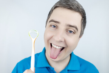 Tongue scraper. Man shows yellow plaque and then performs oral hygiene. Cleaning the tongue with...