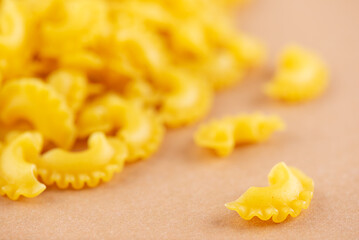 Dry Italian Creste Di Gallo pasta on a beige background. Rooster scallop.