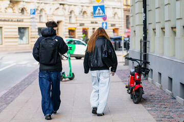 Man and female walking on sidewalk in city with stylish clothes