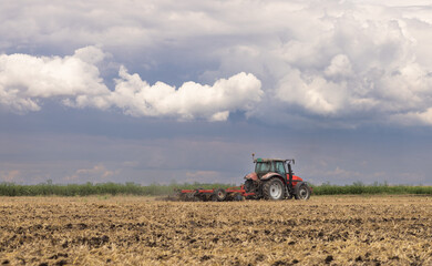 Obraz premium Tractor preparing land with seedbed cultivator.