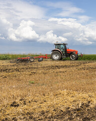 Tractor preparing land with seedbed cultivator.