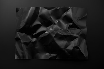 Black crumpled paper isolated on black background - obrazy, fototapety, plakaty