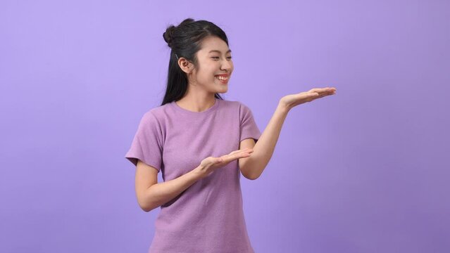 The Asian girl is raising her hand to the side to introduce herself
