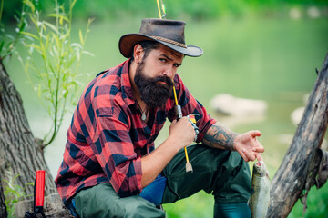 Fototapeta premium Young bearded man fishing at a lake or river. Flyfishing.