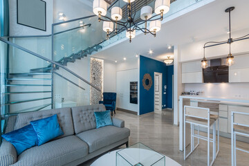 Modern design of the penthouse in bright colors. Glass staircase. Living room with sofa .and...