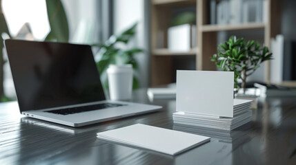 Fototapeta na wymiar A modern workspace featuring a sleek laptop with a blank screen alongside stacks of blank business cards on a polished wooden desk.