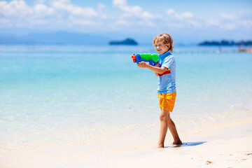 Fototapeta na wymiar Child with toy water gun. Kids vacation beach fun.