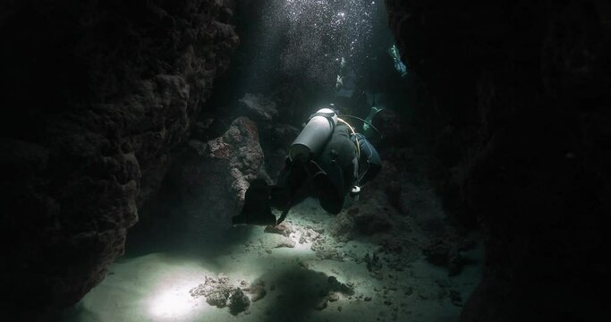 divers pay a visit to a narrow rocky strait on the seafloor