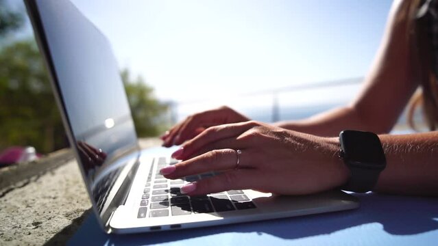 Woman laptop sea. Working remotely on seashore. Happy successful woman female freelancer working on laptop by the sea at sunset, makes a business transaction online. Freelance, remote work on vacation