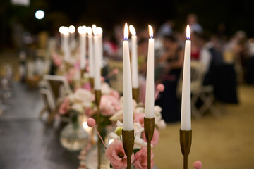 Lighted candles decorating a table during dinner at an outdoor wedding
