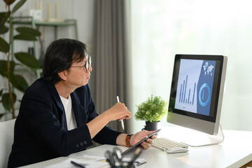 Senior businessman analyzing statistics data on computer monitor