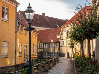 Fototapeta na wymiar Narrow street with half-timbered houses along canal in Bogense, Funen, Denmark