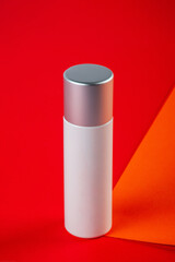 Plastic white tube for cream or lotion. Skin care or sunscreen cosmetic on orange and red background.