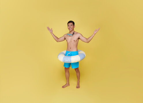 Full body young tourist asian man hold inflatable ring happy summer vacation isolated on yellow background.