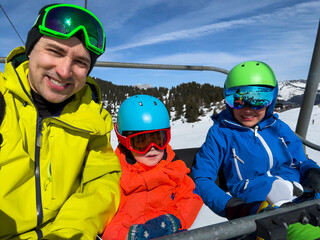 Skiers family, dad with kids capture mountaintop selfie on lift