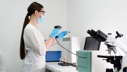 The scientist places blood samples into a modern automated blood chemistry device and monitors the...