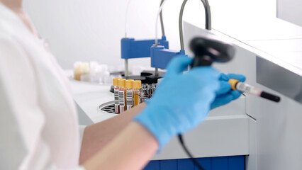 The scientist places blood samples into a modern automated blood chemistry device and monitors the results. Modern research laboratory and medical research.