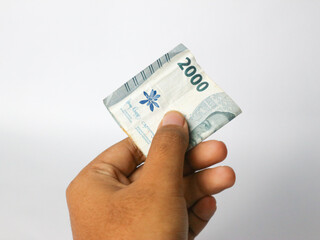 Isolated hand holding Indonesian money amounting to 2000 rupiah.