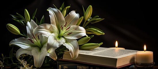 Book, white lily flowers and burning candles on dark background