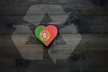 wooden heart with national flag of portugal near reduce, reuse and recycle sing on the wooden background. concept