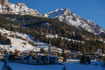 Idyllic dolomite village during winter with snow covered mountains in Alta Badia at nature park...