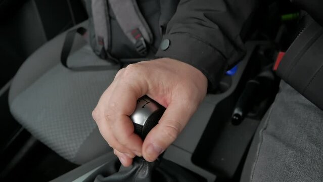 Driver Changing Gears with Manual Transmission Gear Stick. car interior. in the foreground, a gear shifter in a car with a manual transmission, in the background, a passenger seat with a backpack.