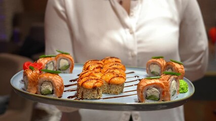 Camera follows female waiter as she carries tray of sushi or rolls ordering client in bar or restaurant. restaurant and hotel business, catering with service staff. Order Delivery.