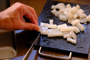 Slicing fresh squid to prepare Spanish paella.