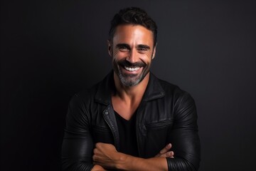 Portrait of a handsome man smiling with arms crossed against black background - obrazy, fototapety, plakaty