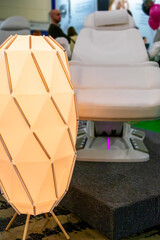 This is a modern vanity chair and white lamp set with a unique design. The lamp is a geometric shaped object with a white base and yellow light.