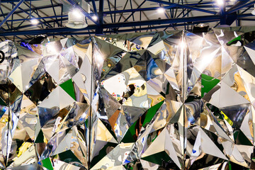 Large mirror wall with a unique design. The wall is covered with a series of triangles in a mosaic pattern. The triangles reflect in the light, creating an interesting visual effect.