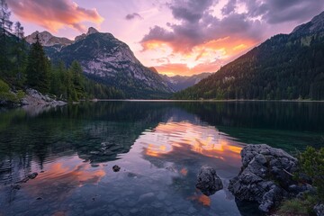 A serene mountain lake surrounded by towering cliffs and dense forest, with a colorful sunset painting the sky in shades of pink and orange