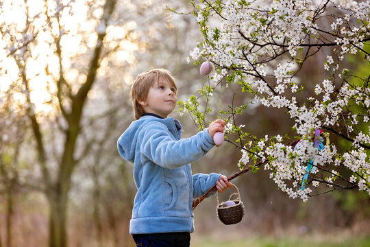 Beautiful blond child, boy, holding twig, braided whip made from pussy willow, traditional symbol of Czech Easter used for whipping girls and basket with eggs