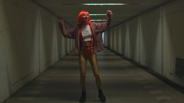 stylish young woman with orange hair dances in a nightclub. Music, dancing and partying with women at the concert.