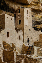 A detailed view of centuries-old Pueblo architecture, showcasing the intricate stonework nestled in a cliff face