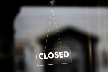 Single closed signed hanging in closed shop front window