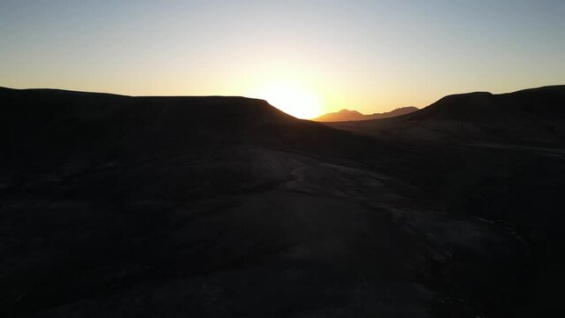 Aerial sunset view over the volcanic ridges of Fuerteventura's barren landscape, extending from El Cotillo to Majanicho with the Faro del Toston in sight