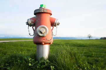 Bright red isolated fire hydrant sits in a freshly cut grass field, real photo