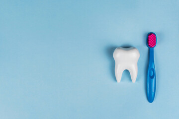 The health of children's teeth. White healthy tooth and baby brush on a blue background. A concept...