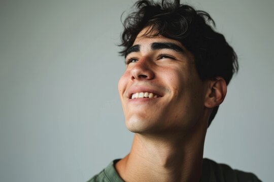 Close up portrait of a handsome young man smiling and looking up.