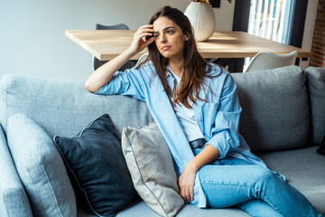 Depressed young woman sitting on couch in the living room at home, Frustrated confused female feels unhappy problem in personal life quarrel break up with boyfriend. - obrazy, fototapety, plakaty