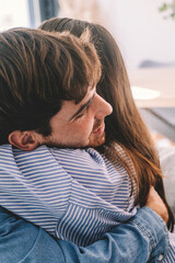 Smiling couple sitting on sofa at home hugging each other happy. Concept of love and happiness