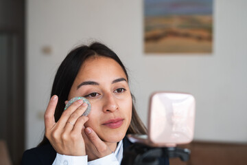Young woman applying makeup with a reusable pad