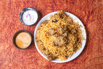 Indian famous mutton biryani dish served on white plate is delicious and fragrant with raita and...