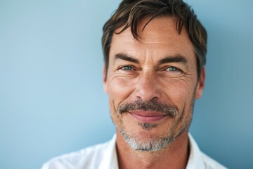 Portrait of a handsome middle-aged man smiling against a blue background