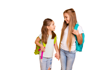 Portrait of two nice attractive lovely cheerful cheery pre-teen girls with colorful backpacks holding hands gossiping talking isolated over bright vivid shine yellow background
