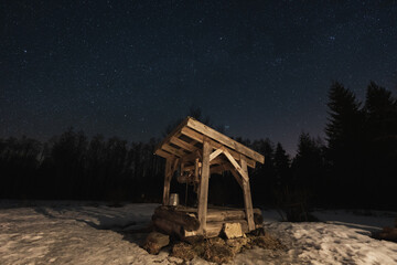 Night scene, landscape astrophoto, old well in the forest with a clear starry sky.