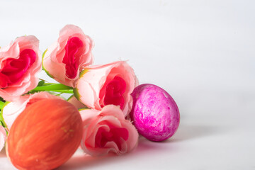 Easter eggs and pink rose flowers on a white background with space for text.